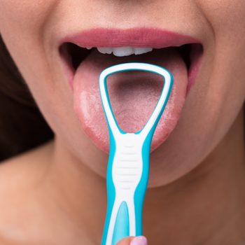 Close-up Of A Woman Cleaning Her Tongue With Cleaner