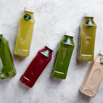 Healthy eating, drinks, diet and detox concept - close up of five plastic bottles with different fruit or vegetable juices for detox plan