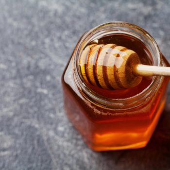 Honey in a pot or jar on kitchen table, top view