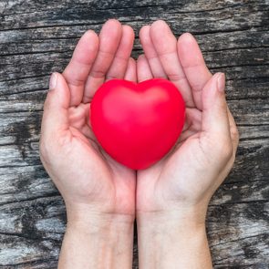 Heart health care medical cardiovascular disease concept and organ donor donation for life giving charity campaign with healthy red love heart on aging woman's  hand support