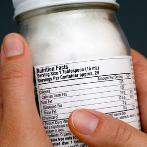 Reading a nutrition facts on organic coconut oil jar. Close-up.