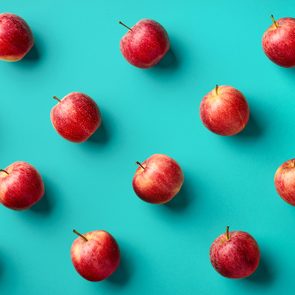 Colorful fruit pattern of fresh red apples on blue background. From top view