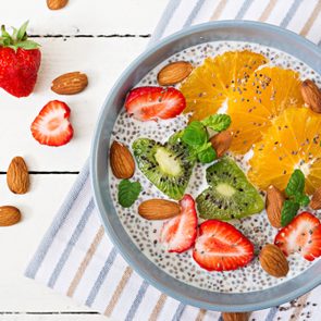 Detox and healthy superfoods breakfast in bowl. Vegan almond milk chia seeds pudding with strawberries, orange and kiwi. Top view. Flat lay