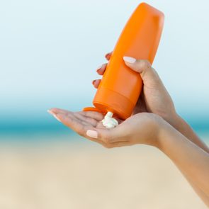 Woman hand apply sunscreen on the beach