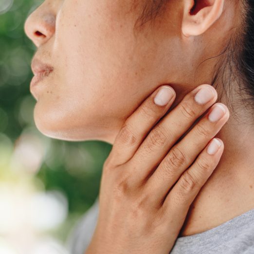 woman holding neck and throat