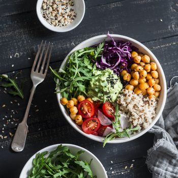 Quinoa and spicy chickpea vegetable vegetarian buddha bowl. Healthy food concept. On a dark background, top view