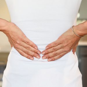 cropped rear shot of woman's hands on lower back