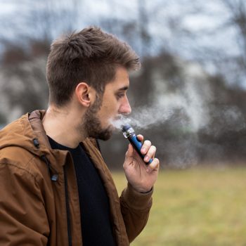 Young male worker smoking electronic cigarette