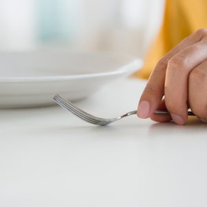 Close up of mixed race man holding fork at table