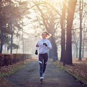 Young woman is running in the cold foggy morning