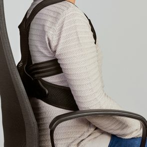 woman wearing a posture corrector in desk chair