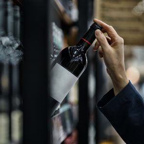 Woman choosing wine bottle in liquor store