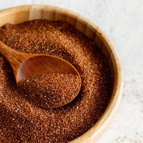 Uncooked teff grain with a wooden spoon close up