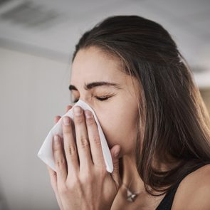 young woman blowing her nose