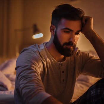 Depressed young man in his bedroom thinking about something