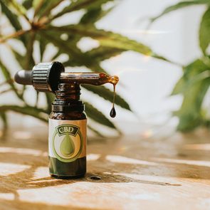 CBD oil Dropper on glass Bottle, surrounded by Cannabis Plants