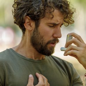 A Man is Using an Asthma Inhaler in Public Park.