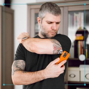 Man is wearing small sensor on the back of upper arm for measuring glucose levels due to diabetes