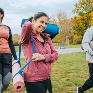 three people walking outside with yoga mats for bone strengthening yoga