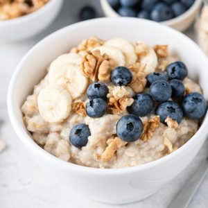 close up of bowl of Porridge oatmeal with banana blueberries and walnuts