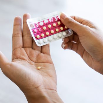 hands holding a package of birth control and removing from package